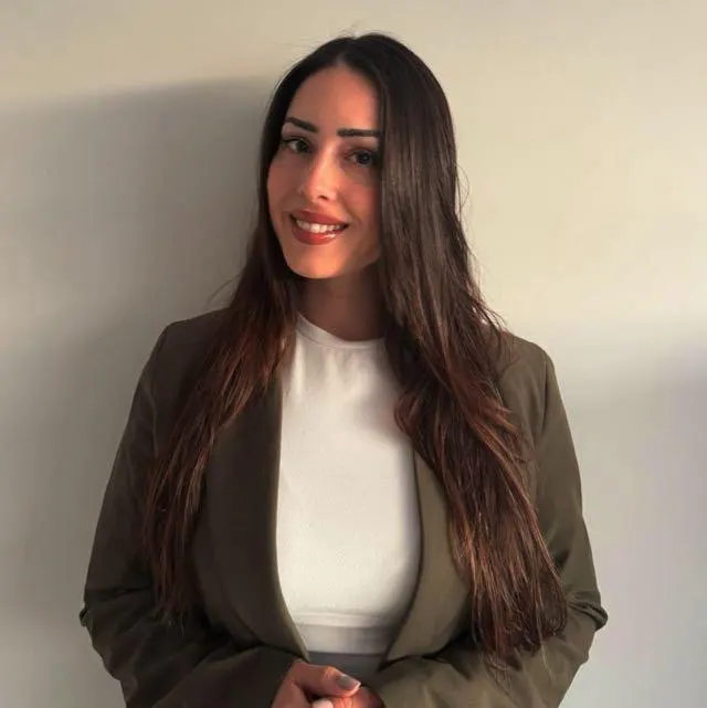 Portrait of Celine Micallef, smiling, in an olive blazer